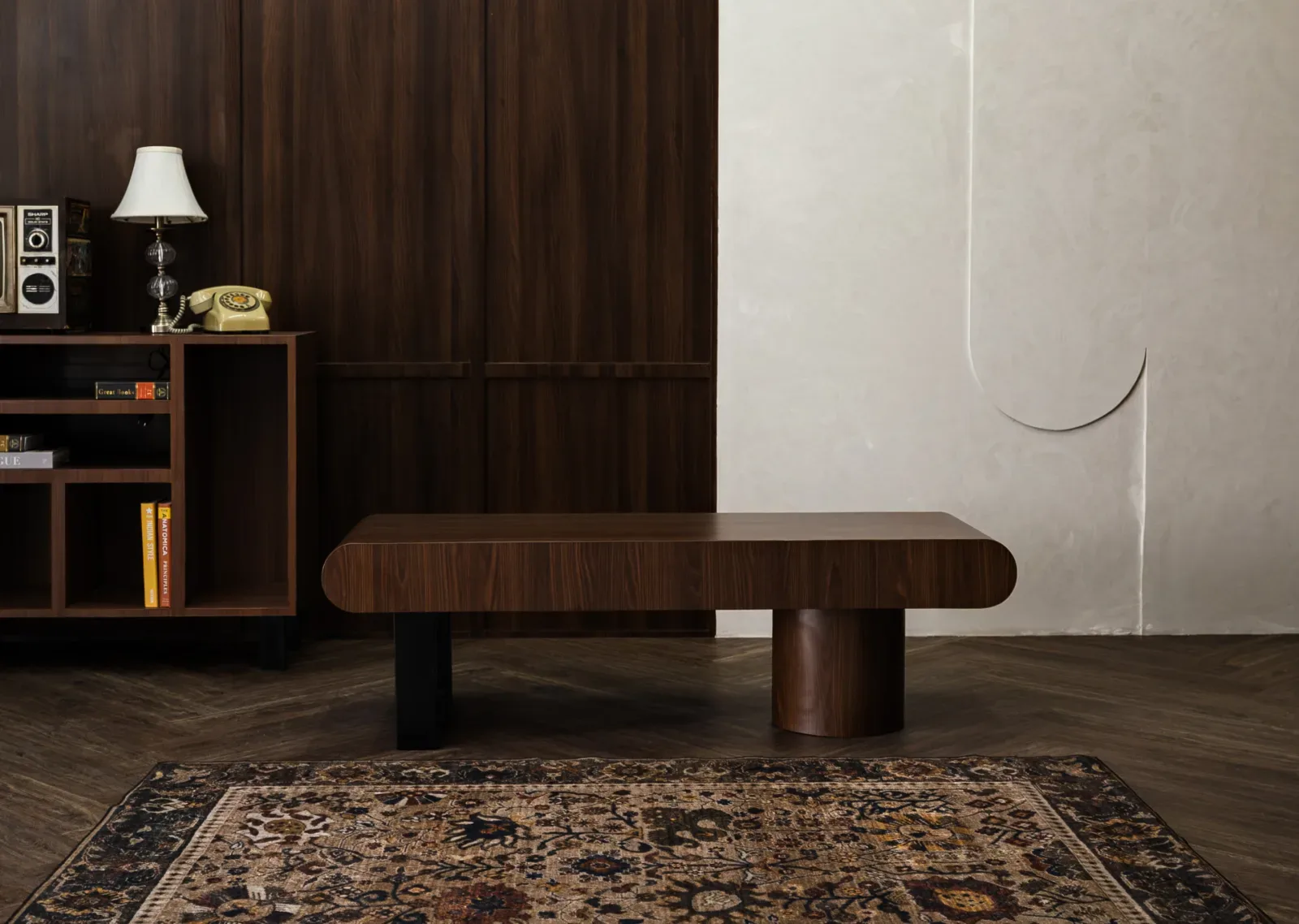 Set studio mid-century dengan dinding panel kayu walnut, kabinet retro berlampu meja, telepon putar krem, meja rendah kayu, dan karpet Persia di lantai parket herringbone.