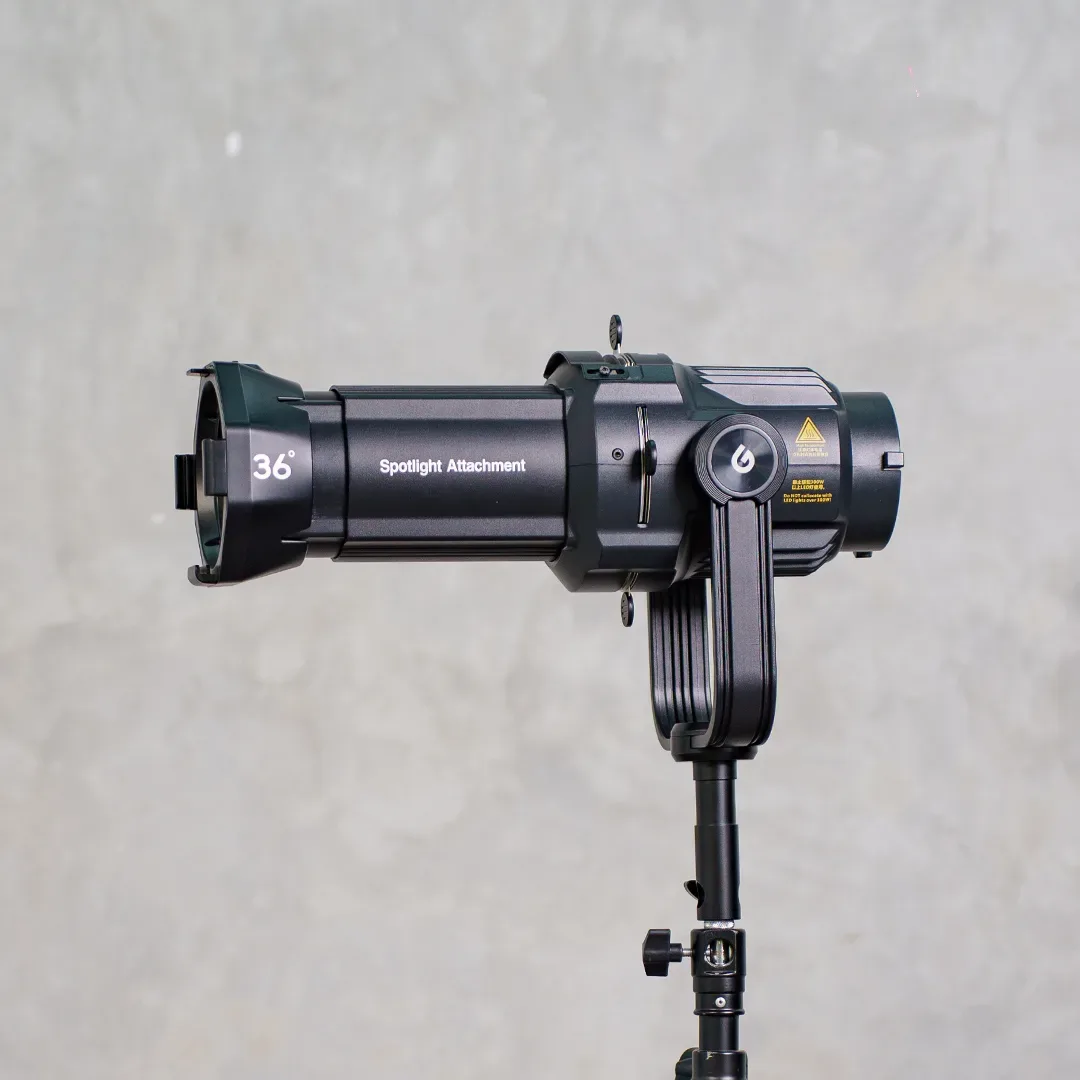 Lampu LED COB Godox di light stand dengan aksesori Spotlight Attachment bertanda 36 derajat terpasang di depan lensa.