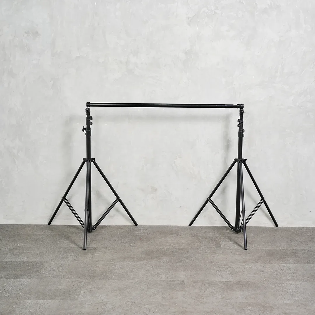 Set penyangga backdrop berupa dua light stand tripod hitam dengan crossbar teleskopik terpasang di antaranya.